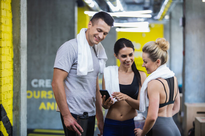 Three friends looking at phone after a workout