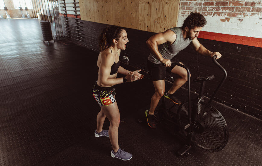 Female personal trainer coaching male on exercise bike